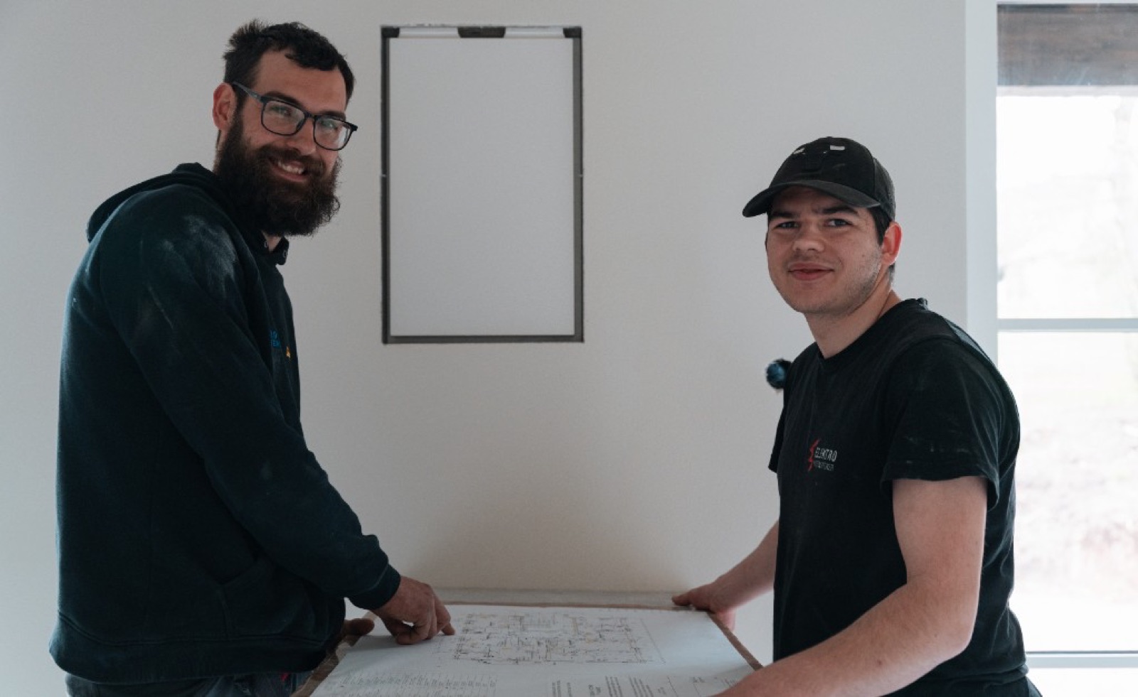 Elektroinstallateure prüfen einen Installationsplan vor Ort